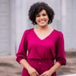 woman in red long sleeve shirt standing near white wall during daytime